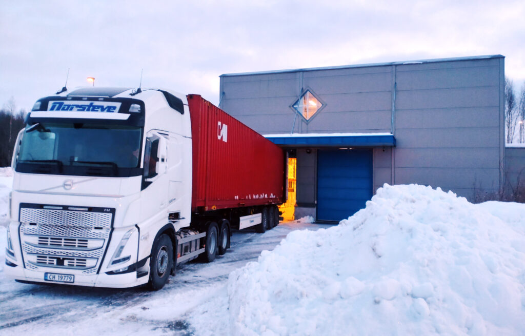 En lastebil med lasterom har rygget inn til døren til lageret hos Næringstjenester for å levere eller hente varer.